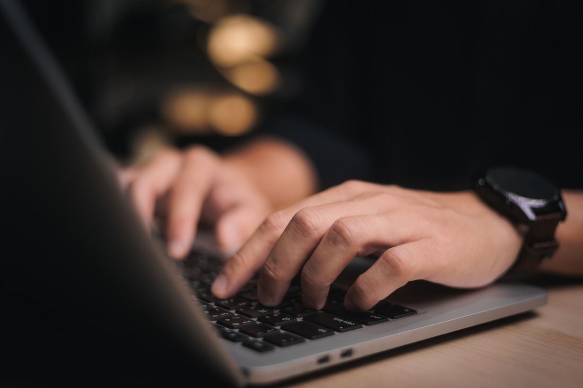 hands-typing-on-laptop-dark-background