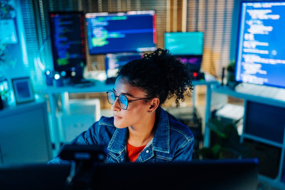 female developer with glasses working at multiple code screens