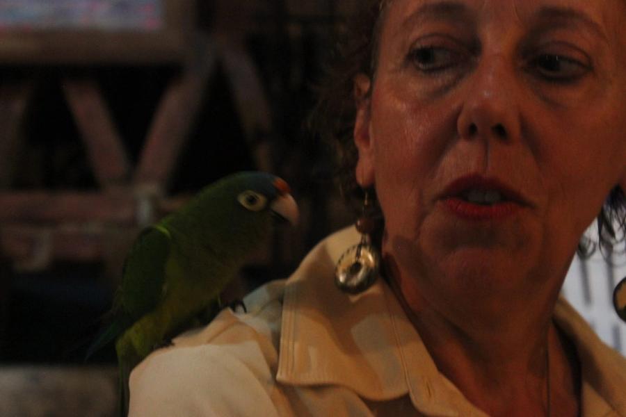 Me with a green parrot on my shoulder, the two of us turned toward each other