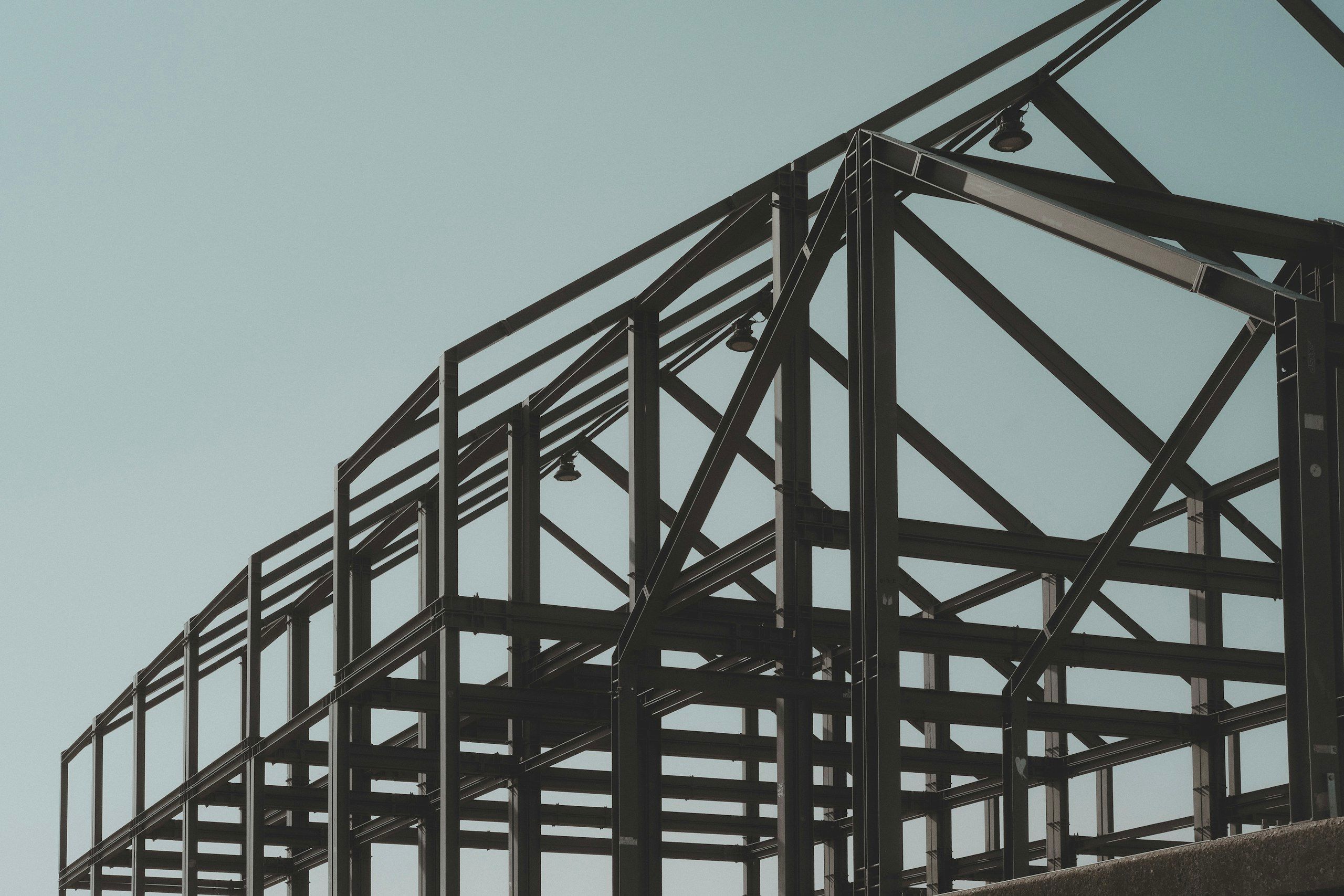 Steel skeleton of a building under construction against a pale sky