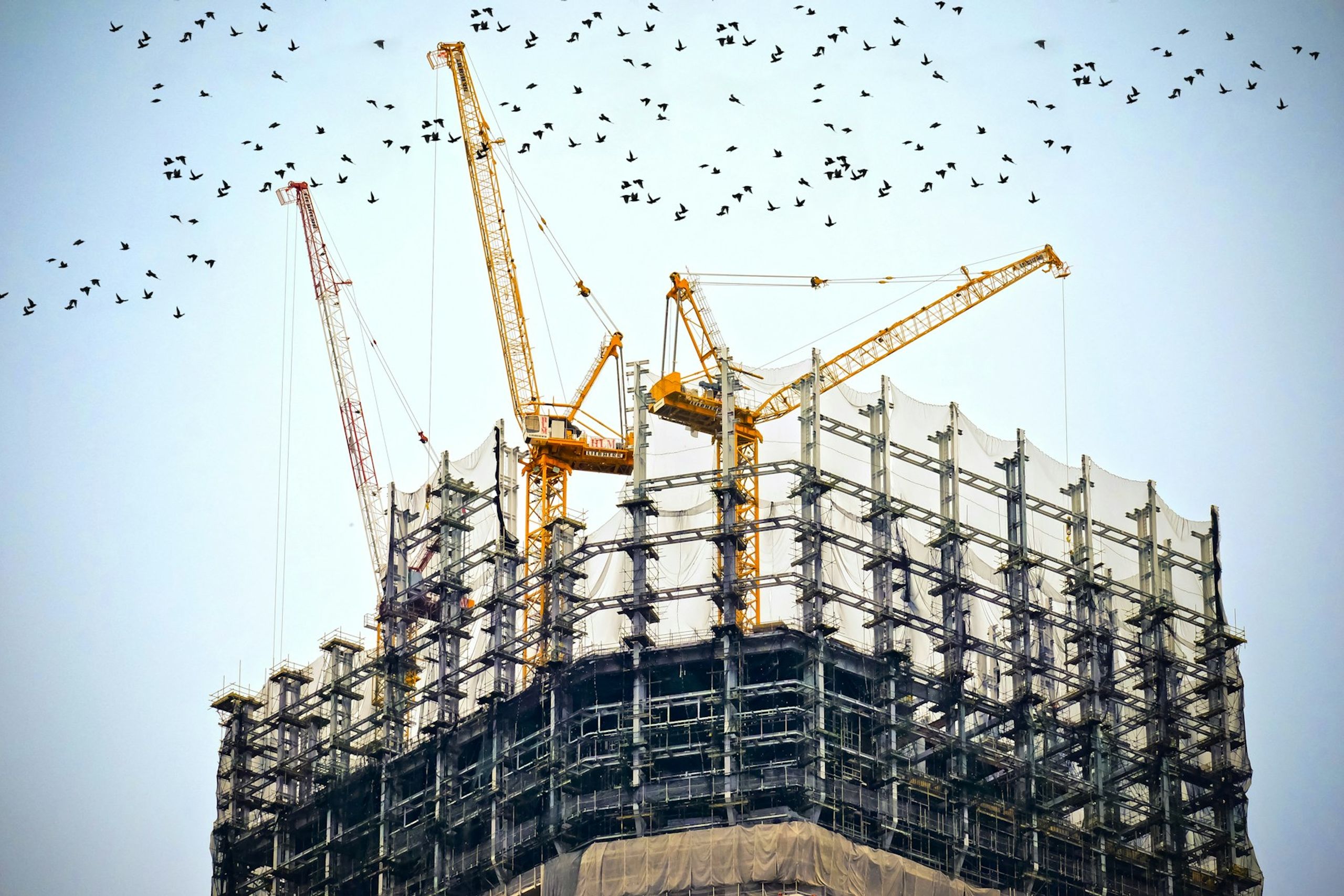 Tower cranes working on top of a high-rise under construction