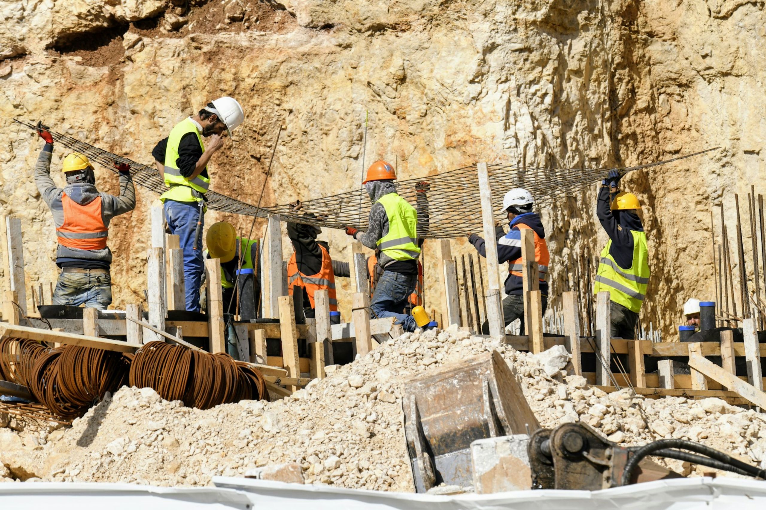 Construction crew in hard hats placing rebar on a building site