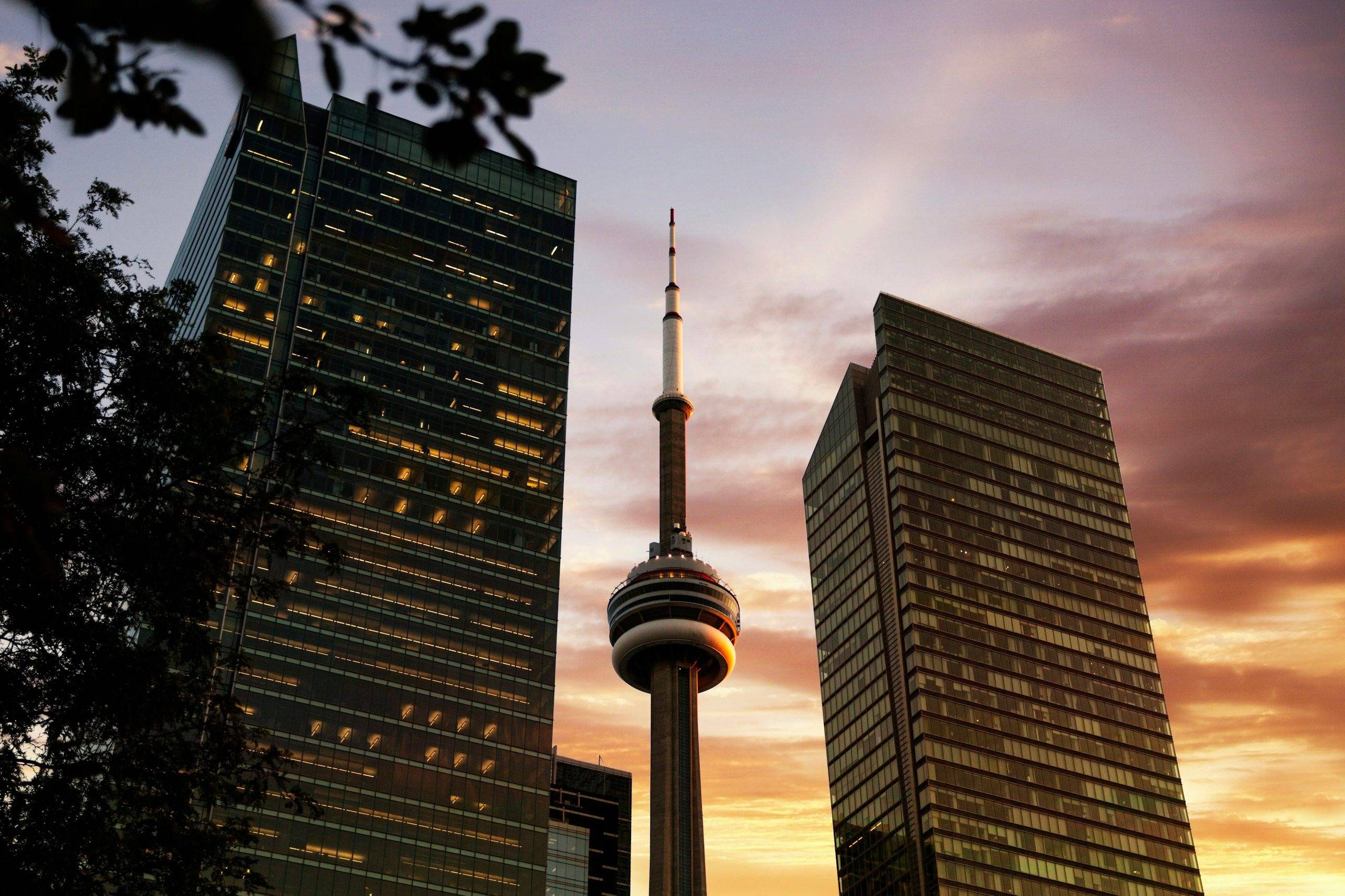 The CN Tower between two office towers in downtown Toronto at sunset