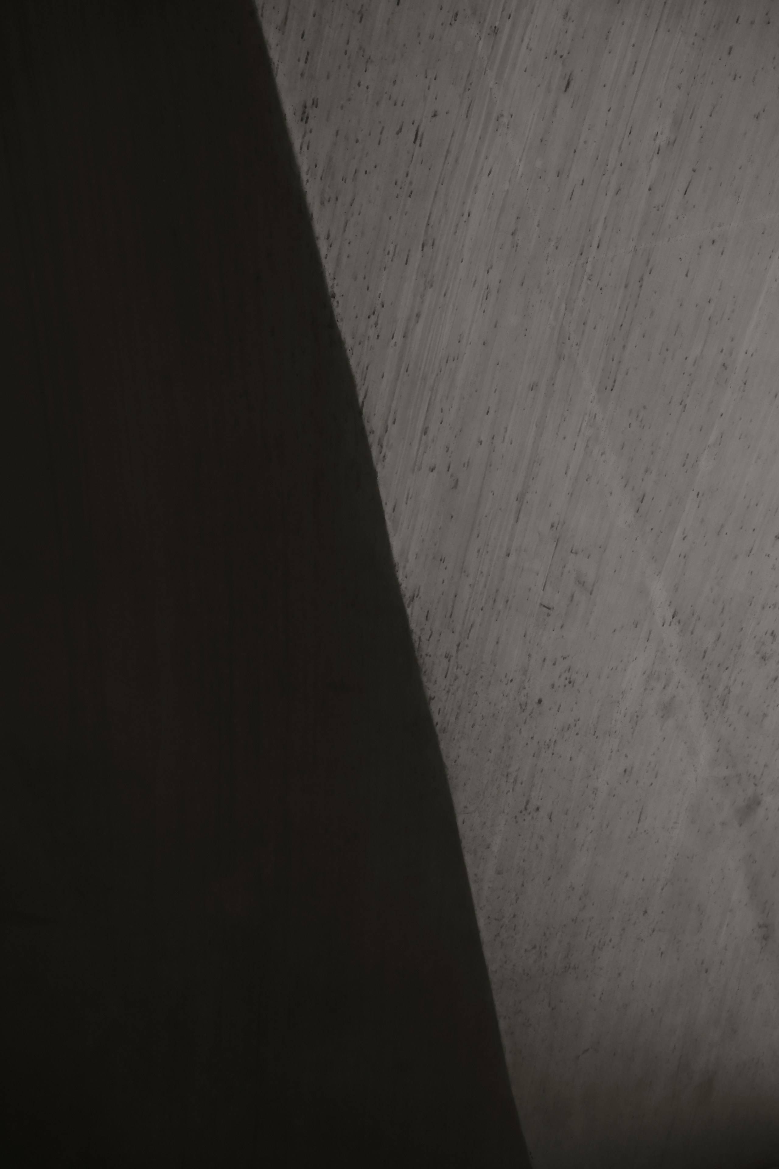 A deep shadow falling across a raw concrete wall