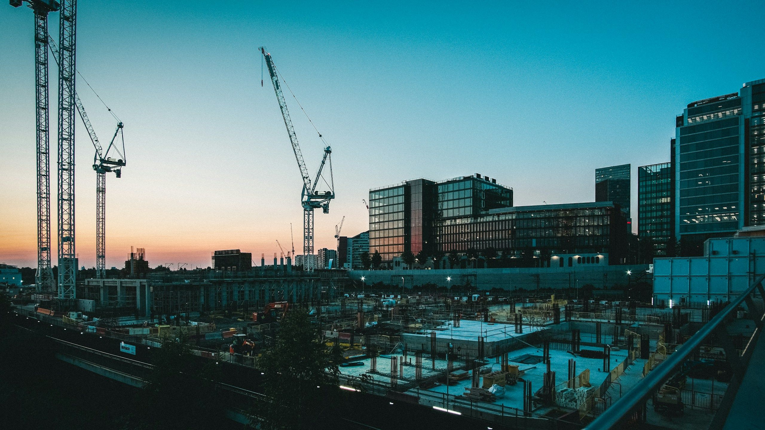Tower cranes over a city construction site at dusk