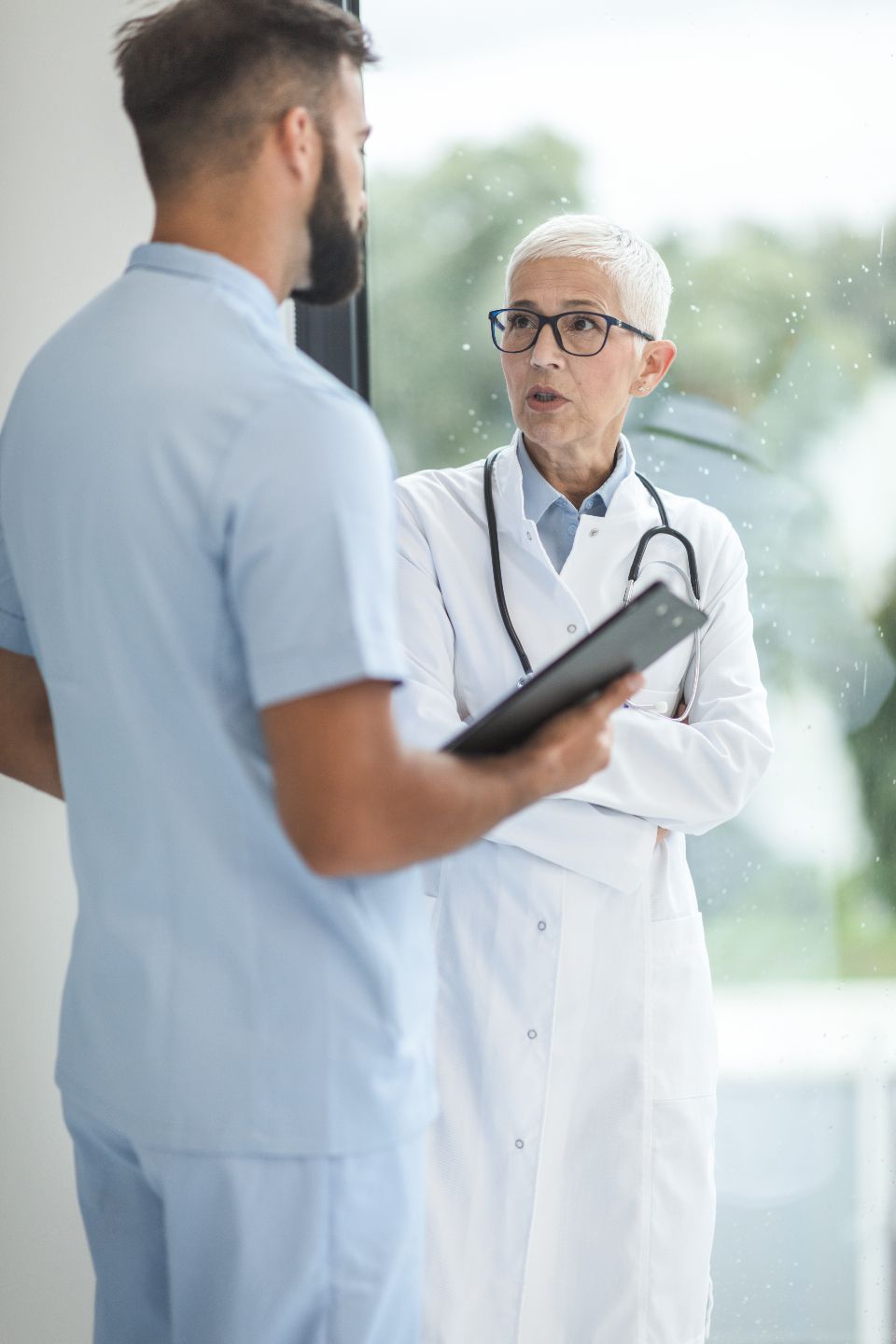 A smiling doctor standing in a clinic hallway.