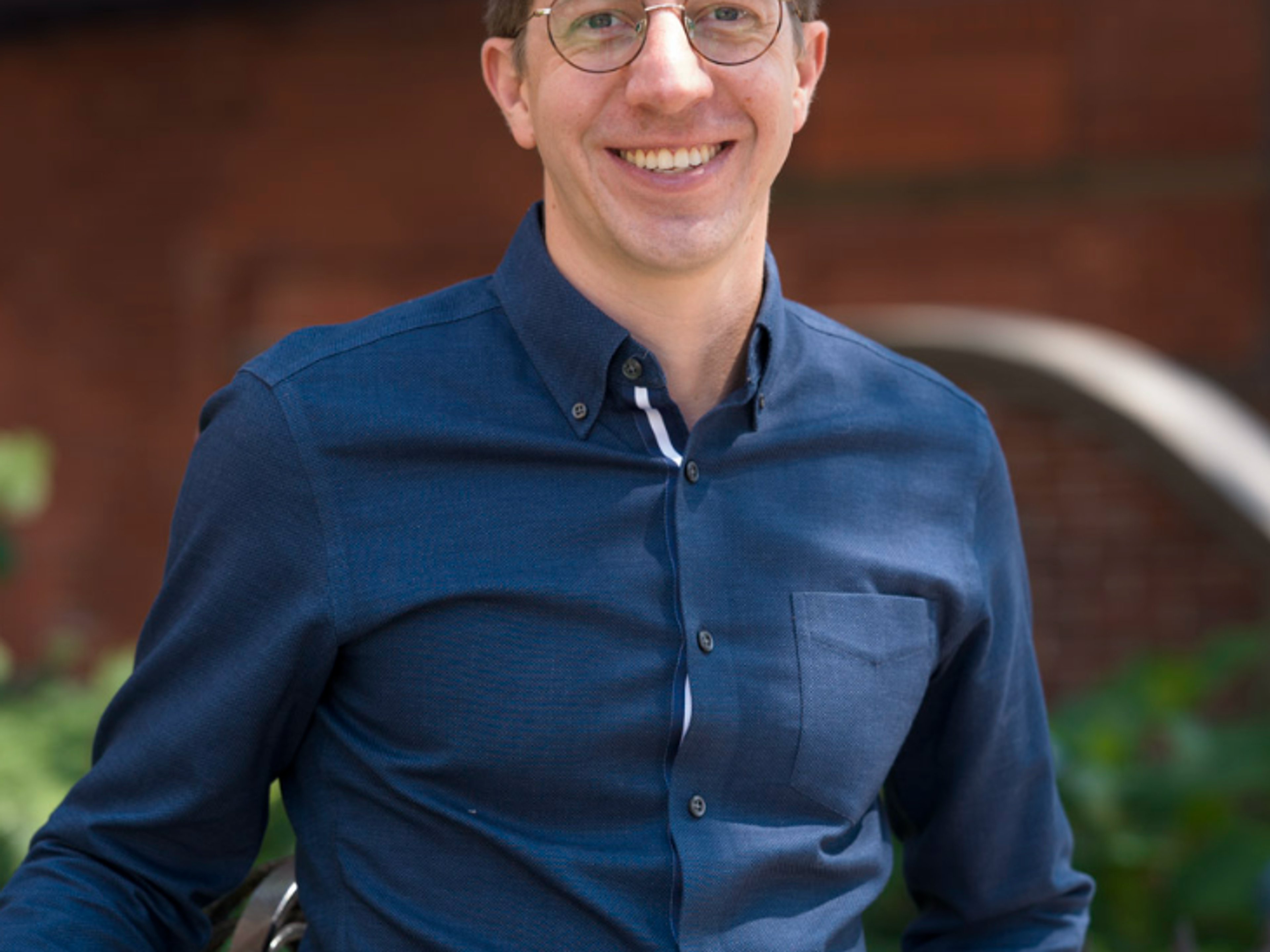 A young man with short hair smiling outdoors in Back Bay, Boston.