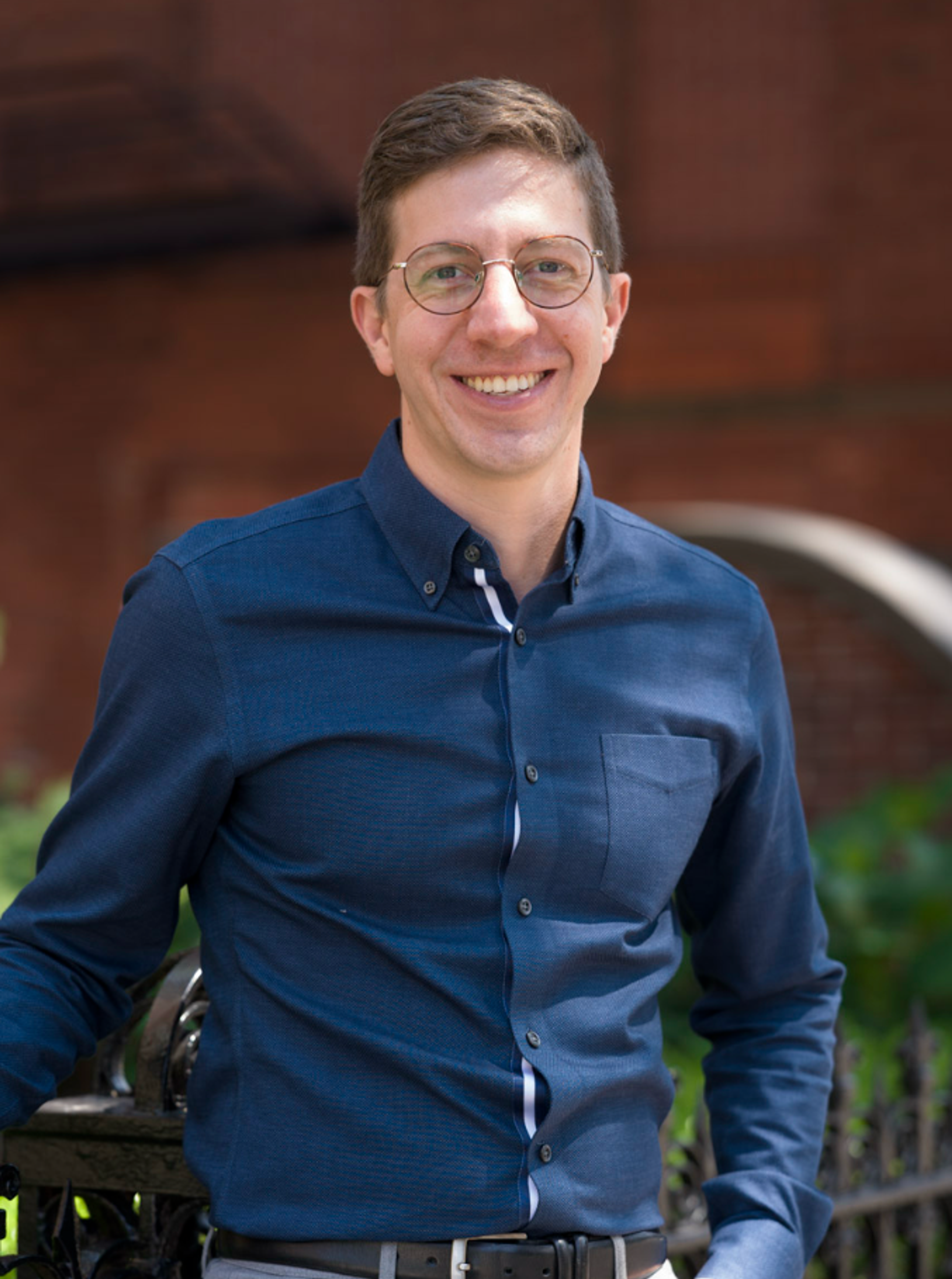 A young man with short hair smiling outdoors in Back Bay, Boston.