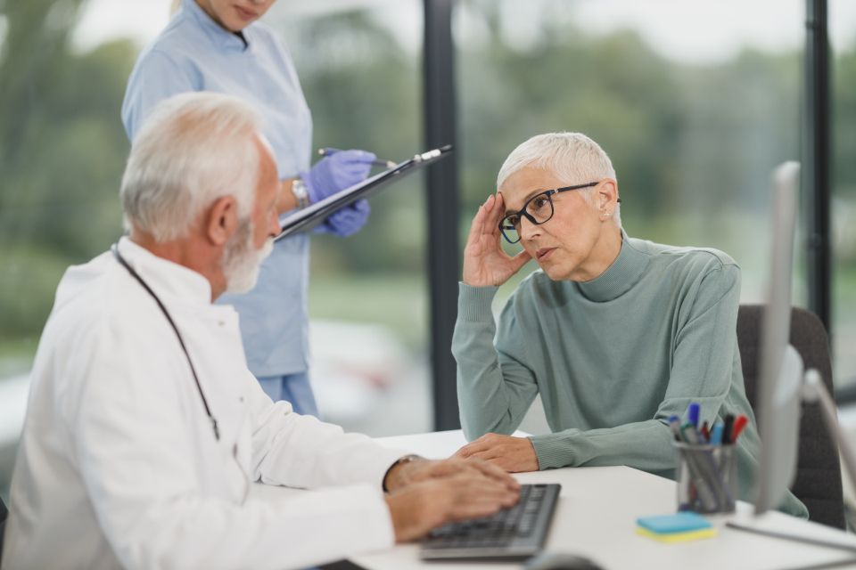 A clinician talking with a patient across a desk.