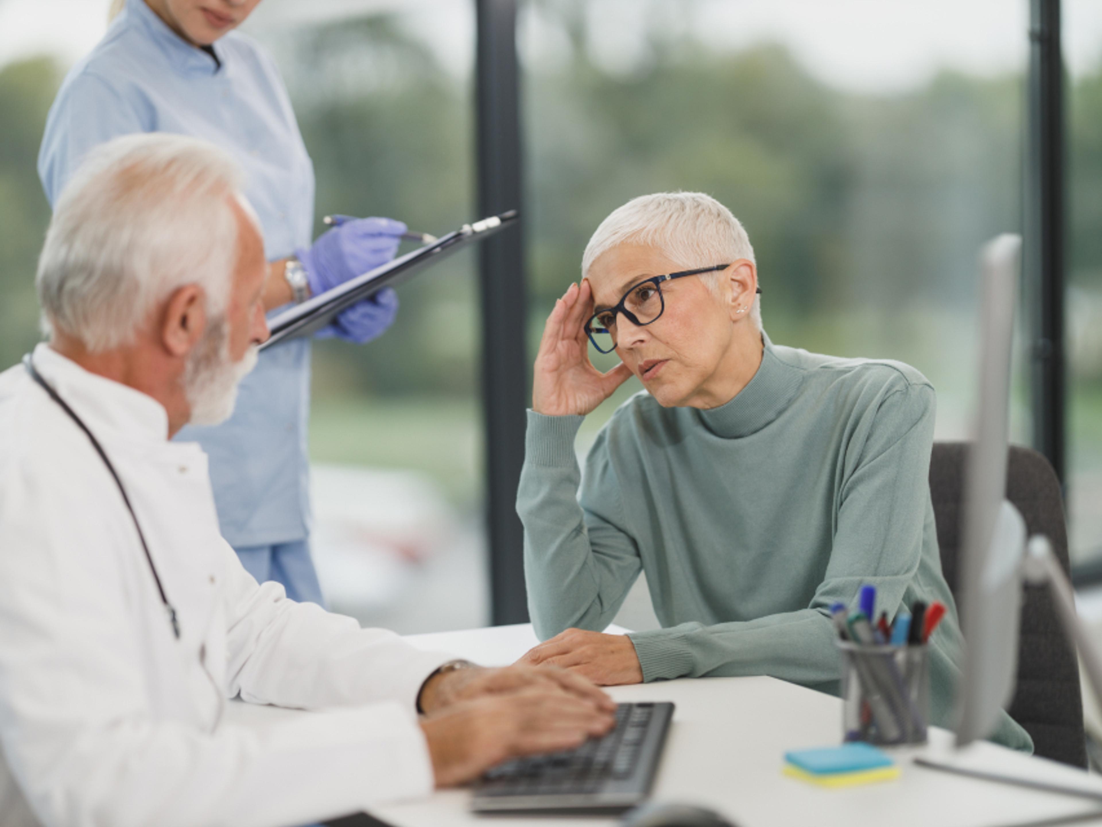 A clinician talking with a patient across a desk.