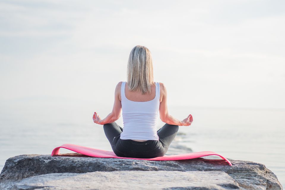 A person meditating outdoors at sunrise.