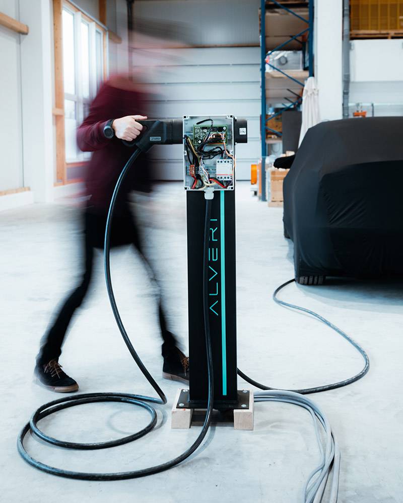 Person in motion blur at an open prototype of the Alveri charging station in a workshop