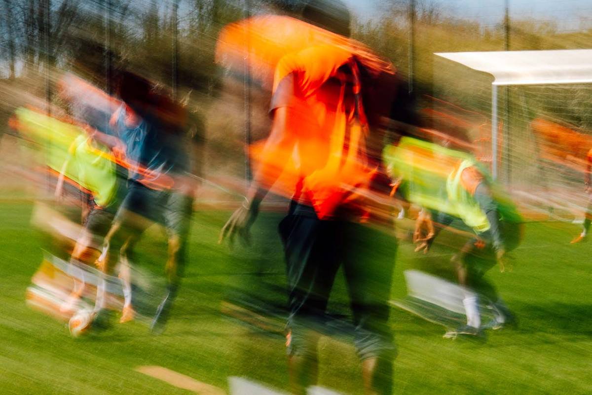 Trainingsspiel in Bewegungsunschärfe, Spieler in orangen Trikots und gelben Leibchen