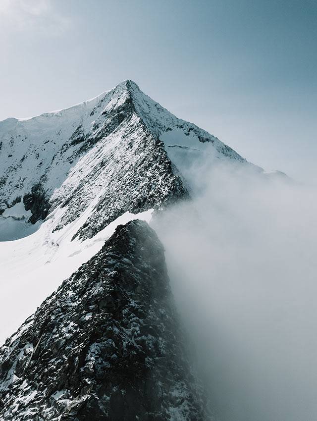Snow-covered summit ridge rising out of the clouds