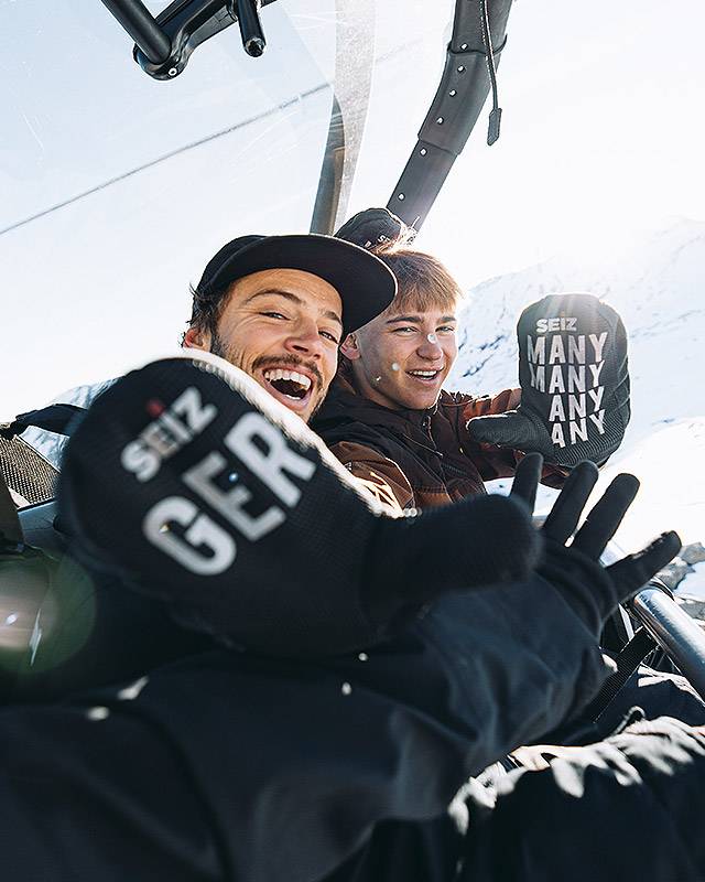 Zwei lachende Snowboarder im Sessellift