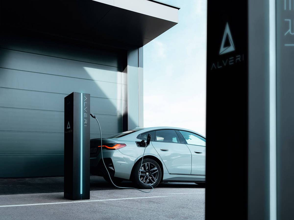 Elektroauto lädt an einer schwarzen Alveri-Ladesäule vor einem modernen Gebäude
