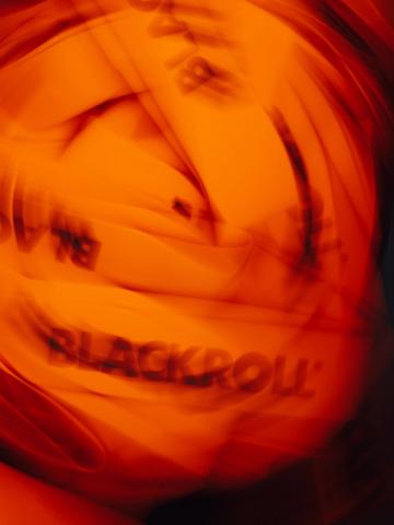 Unscharfe Nahaufnahme mehrerer Filmrollen in einer Tasche, beleuchtet von intensivem orange-rotem Licht.