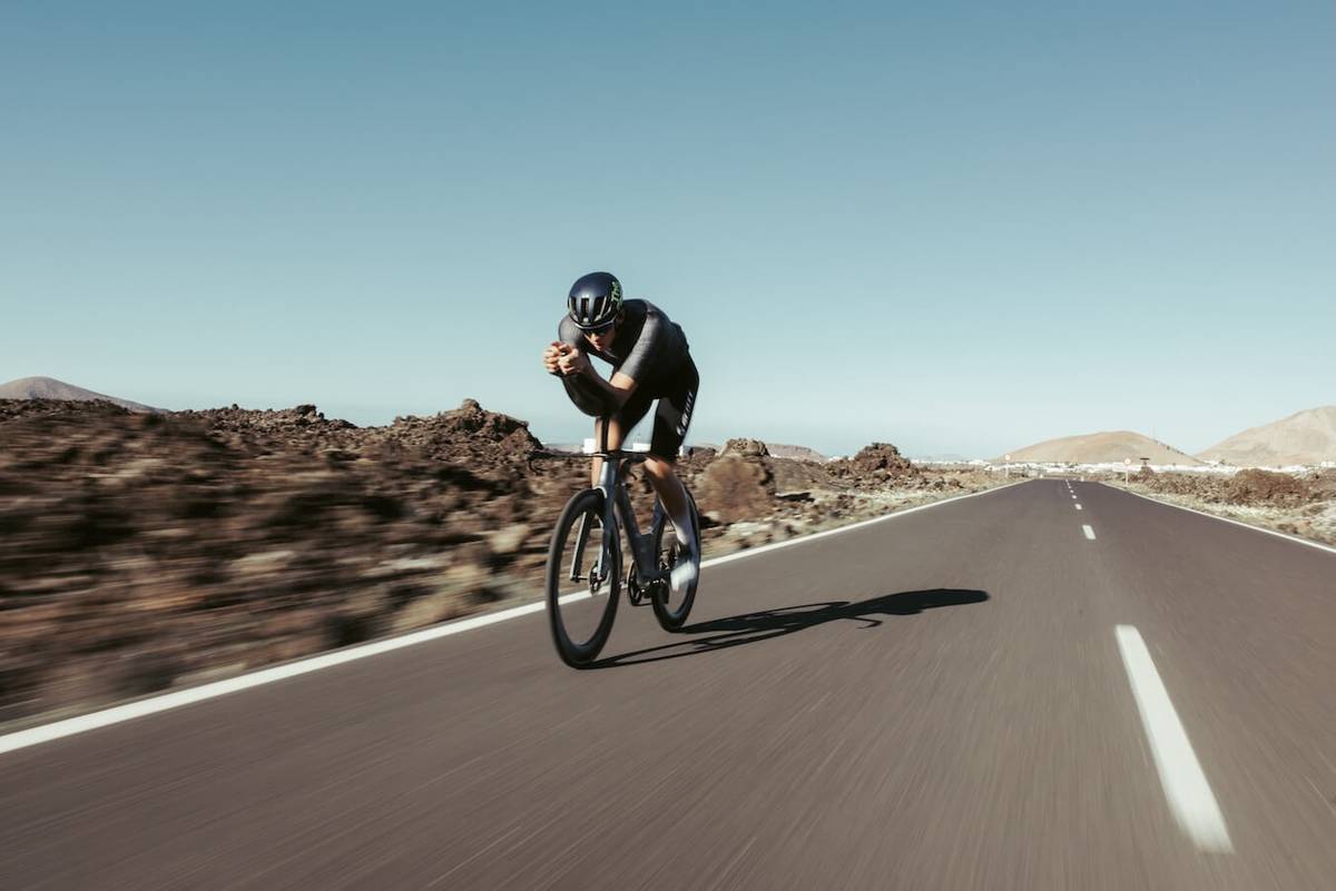 Cyclist on a time-trial bike on a desert road, the landscape blurred by motion