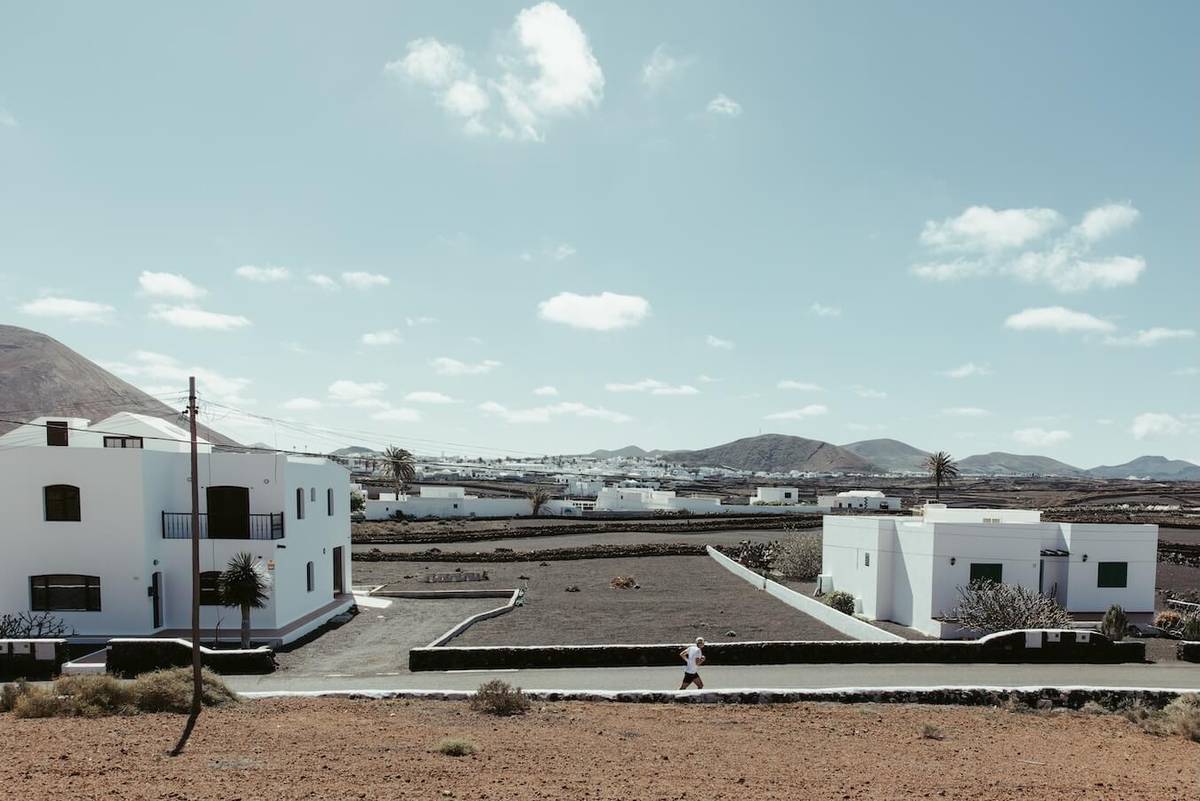 White houses in a barren volcanic landscape, a runner small in the distance