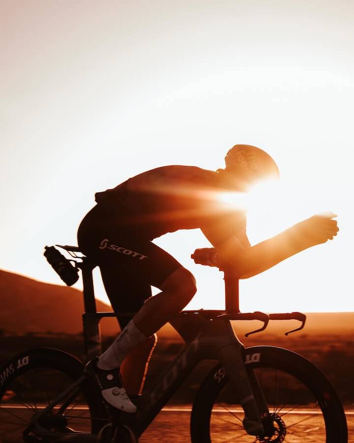 Silhouette of the cyclist on his time-trial bike against the low sun