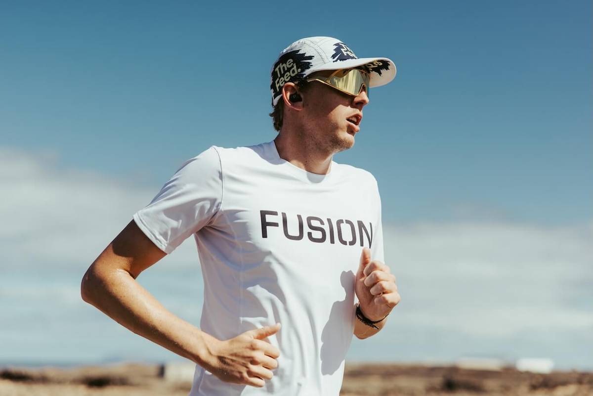 Runner in a white shirt, cap and sunglasses in front of a blue sky