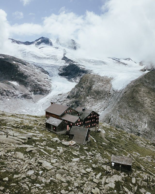 Mountain hut on rocky ground below a glacier