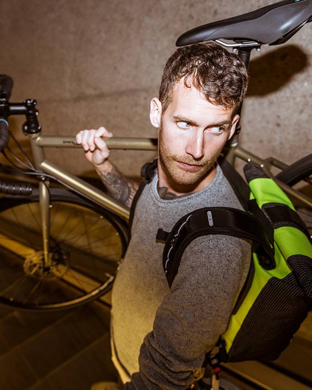 Man carrying a bike on his shoulder, looking back
