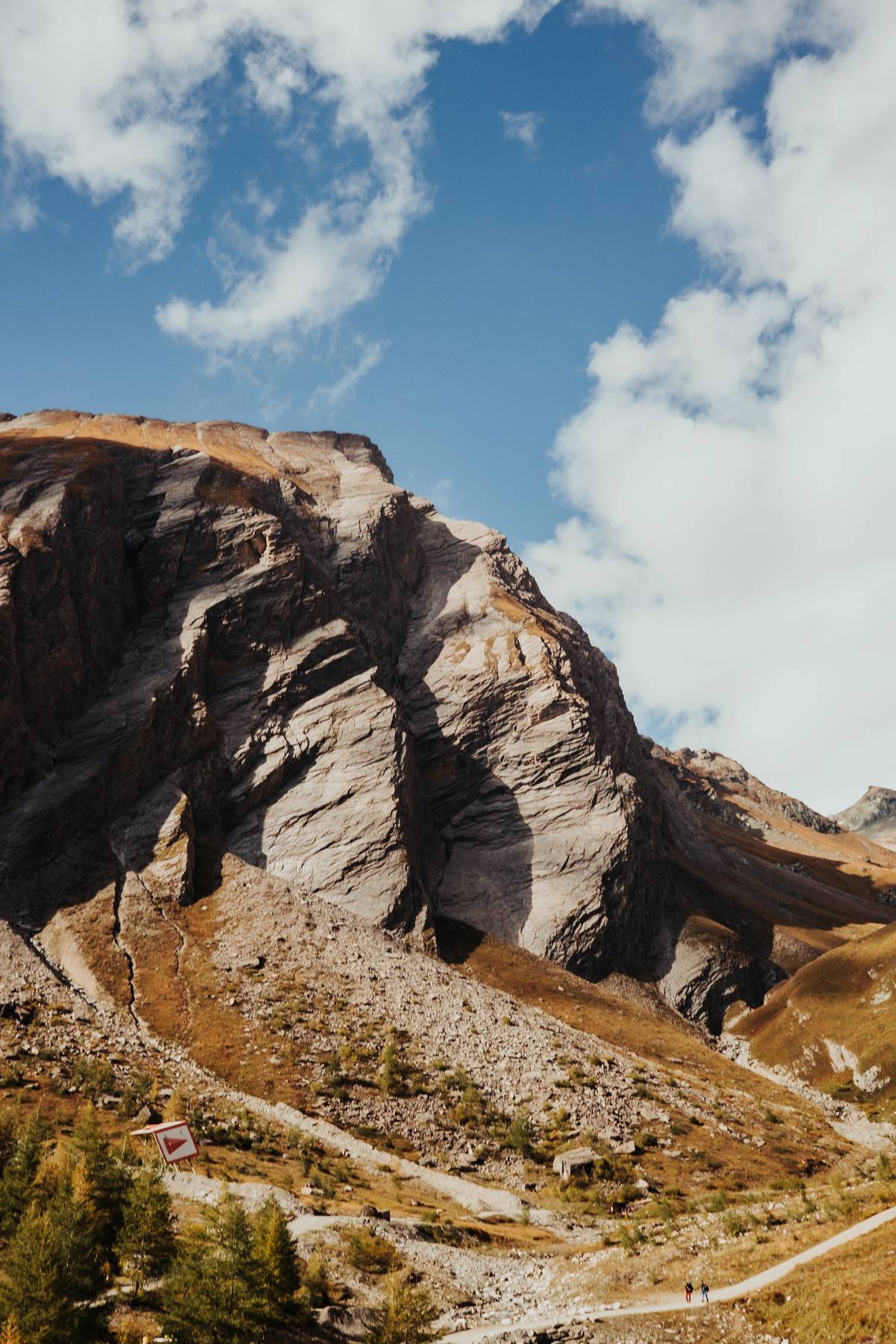 Rocky mountainside with a winding path under a blue sky with clouds