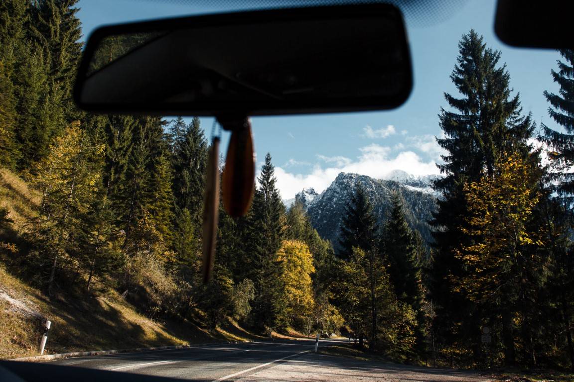 View through a windscreen onto a mountain road through autumn forest
