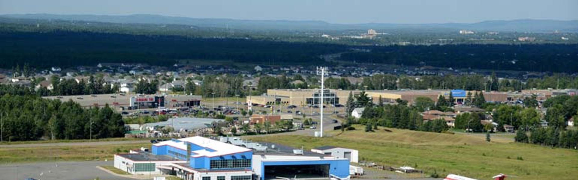 Aviation Centre of Excellence building with small aircraft parked on the apron and a runway in front