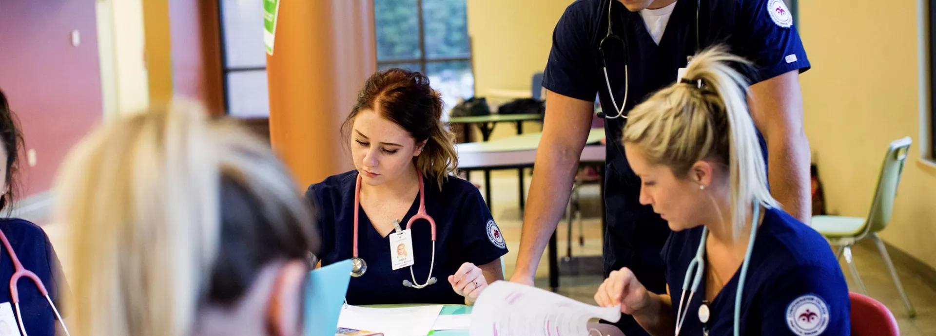 Nursing students studying together with textbooks and notes