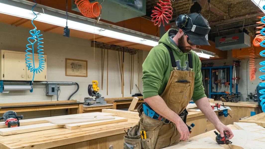 Student assembling wood components at a workbench in the carpentry shop