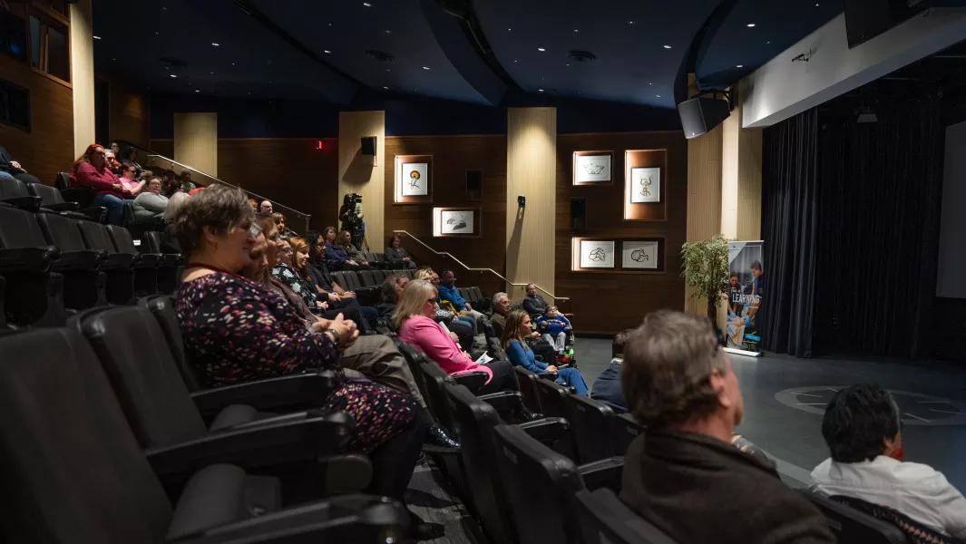 Audience seated in a campus theatre watching a presentation