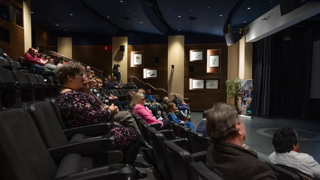 Audience seated in a campus theatre watching a presentation