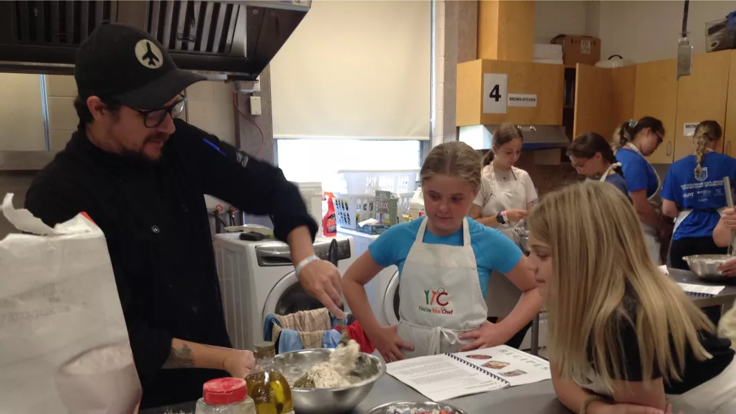 Chef instructing youth participants in a cooking class at summer camp