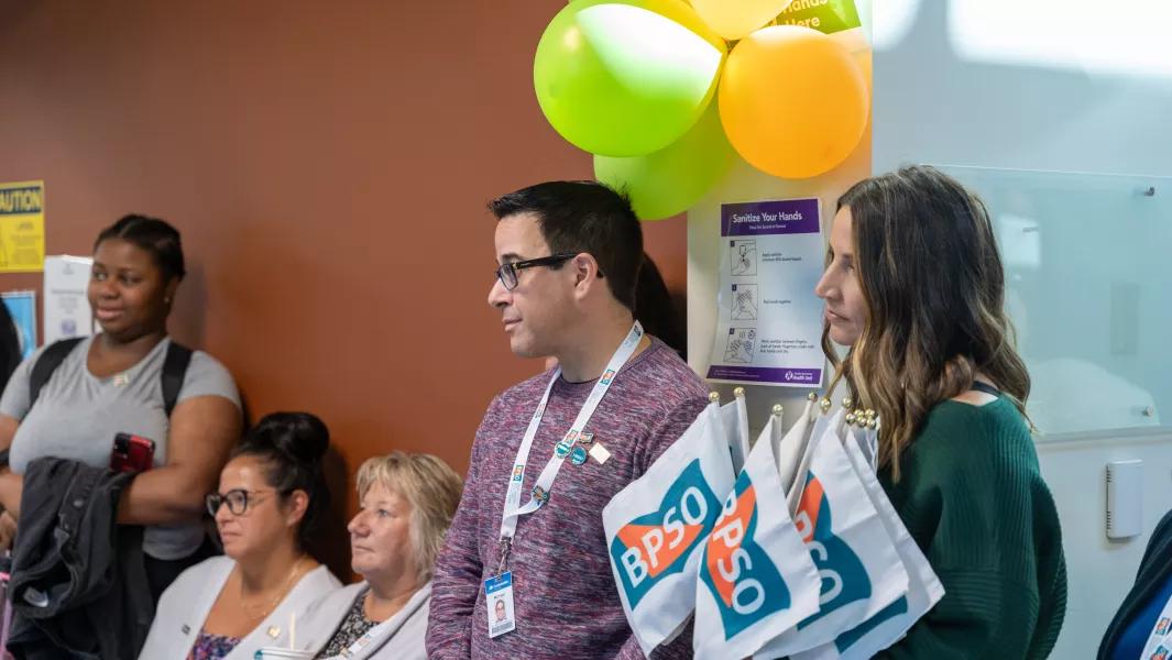 Attendees listening during a Confederation College hallway event decorated with balloons