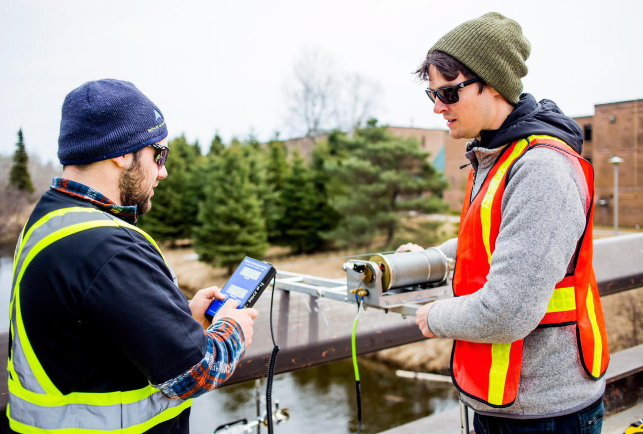 Students conducting environmental monitoring with field equipment at an outdoor testing site
