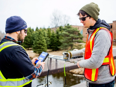 Students conducting environmental monitoring with field equipment at an outdoor testing site