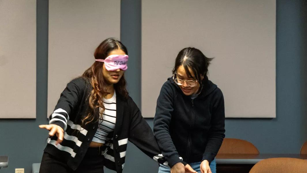 A blindfolded student being guided through a classroom exercise
