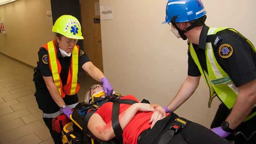 Paramedic students transporting a mock patient on a stretcher during a training scenario