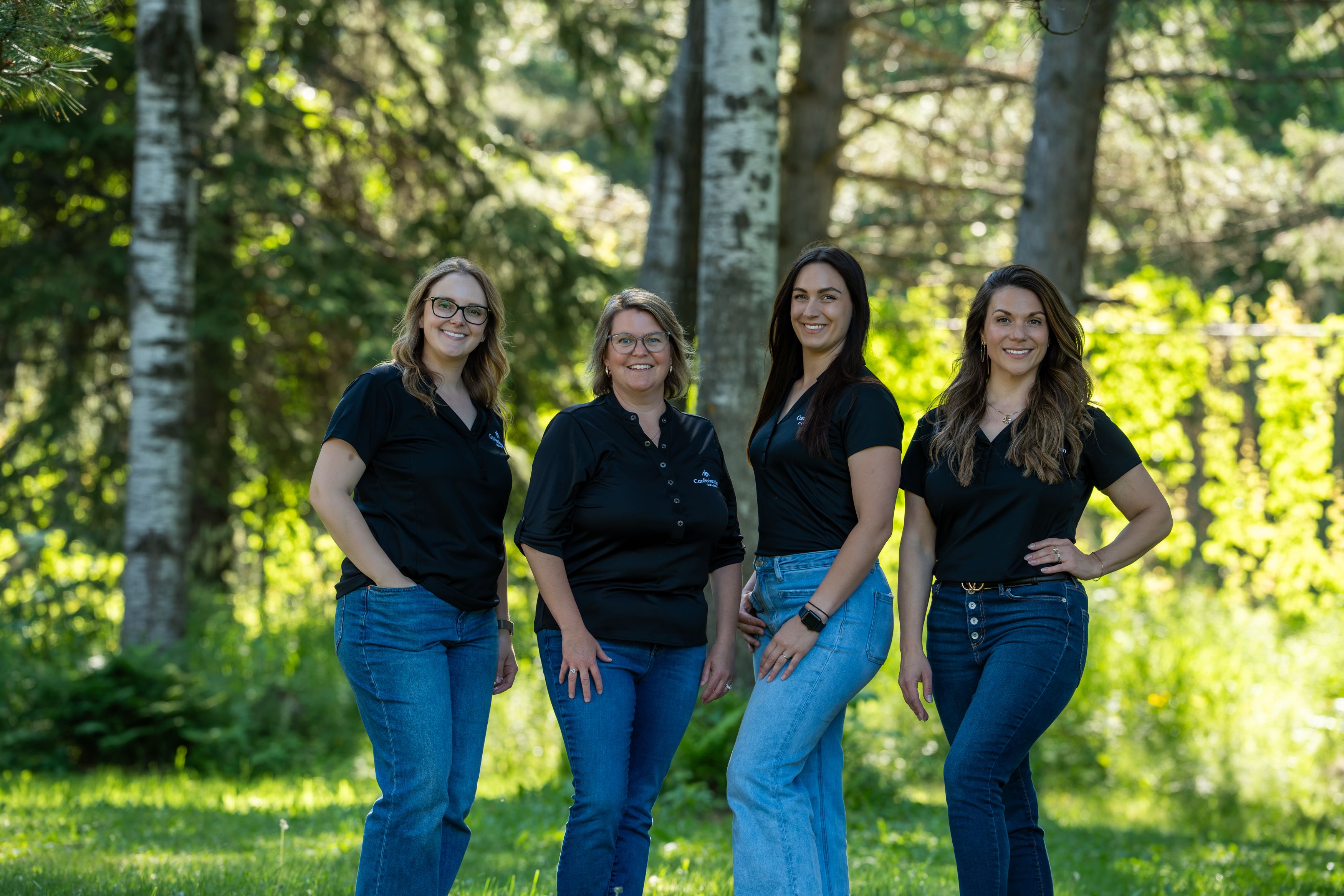 Recruitment Team in black shirts and jeans standing outdoors among trees and grass