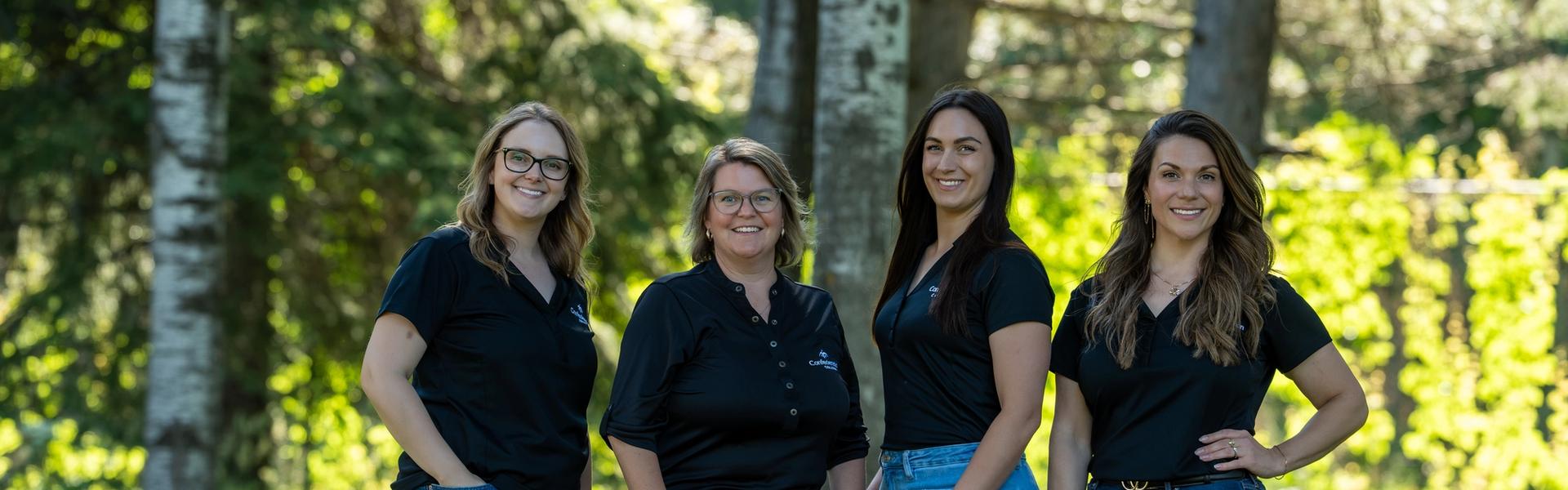 Recruitment Team in black shirts and jeans standing outdoors among trees and grass