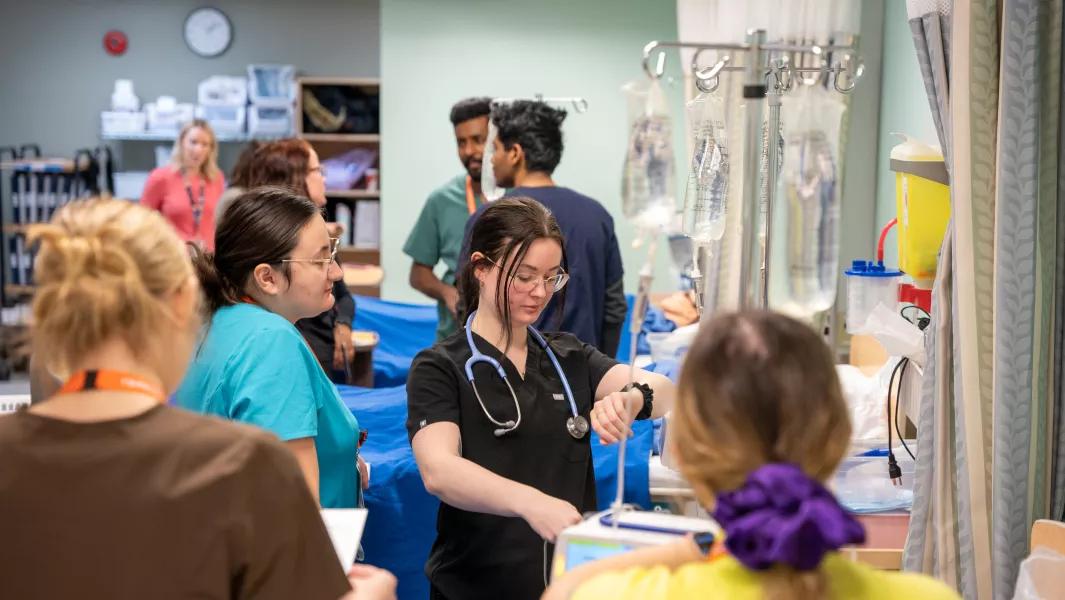 Students working through clinical skills activities in a busy lab setting