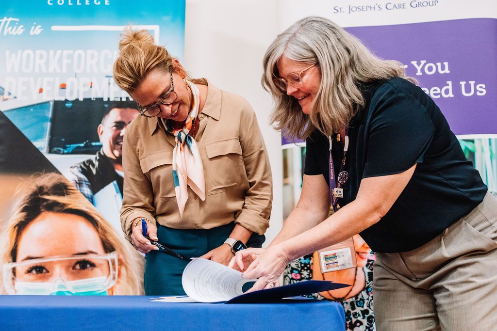 Two professionals reviewing and signing documents at a community partnership event