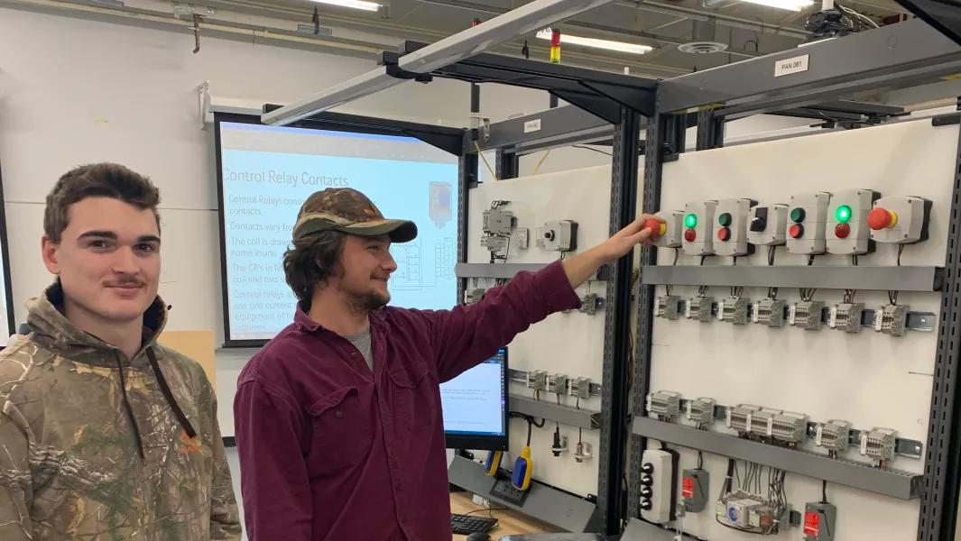Students operating controls on an electrical relay training board