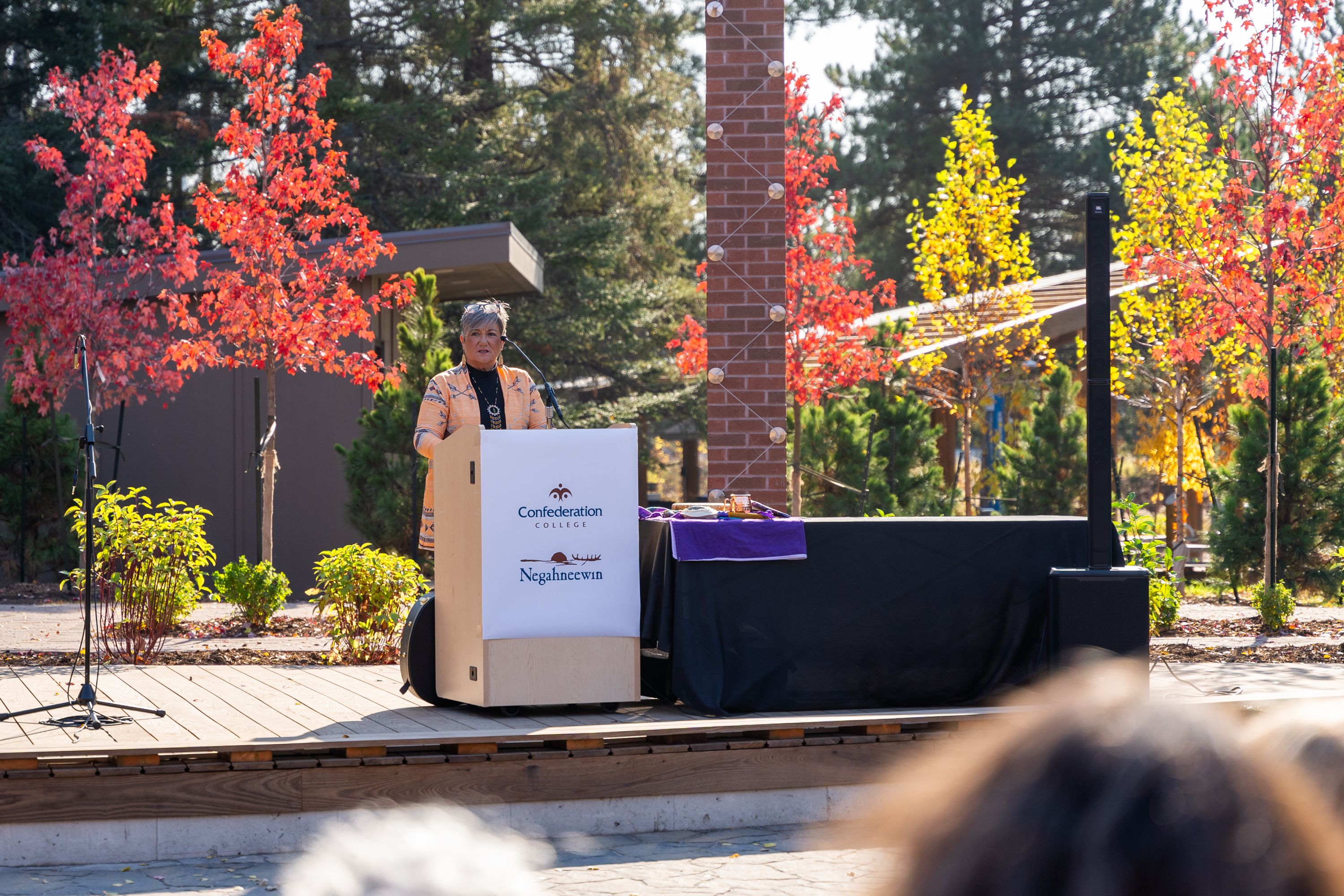 Speaker at Confederation College outdoor gathering during a campus Indigenous event in autumn