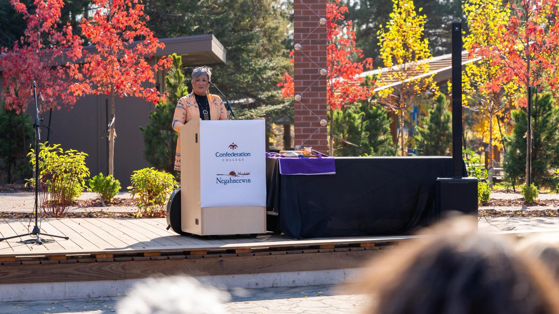 Speaker at Confederation College outdoor gathering during a campus Indigenous event in autumn