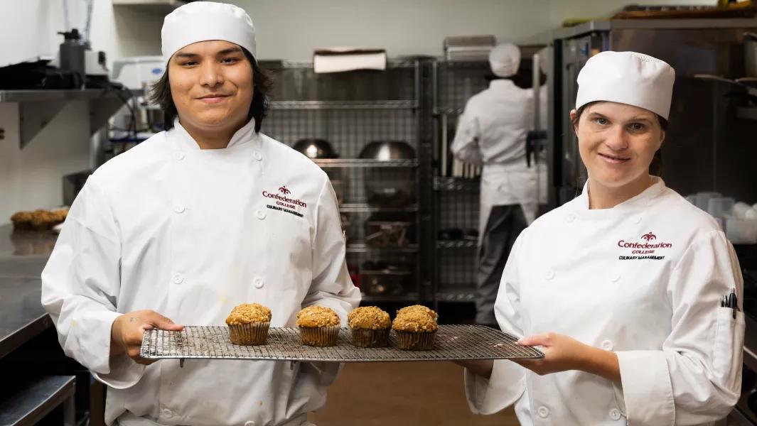 Culinary students presenting freshly baked muffins