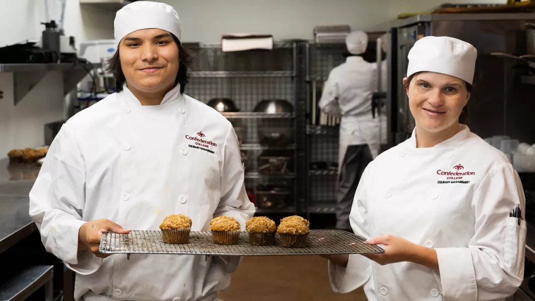 Culinary students presenting freshly baked muffins