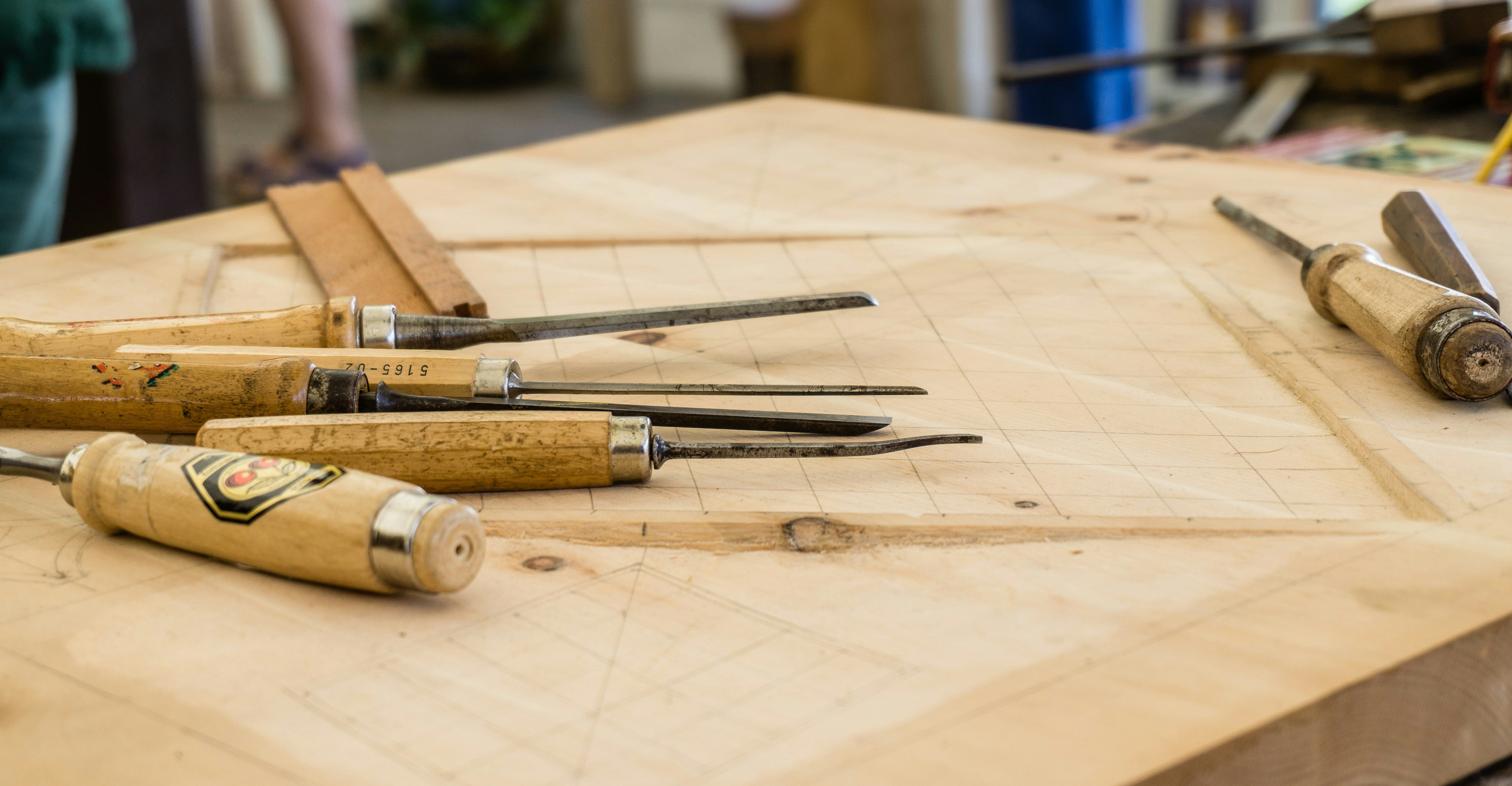 Woodworking chisels and carving tools laid on a marked wooden work surface